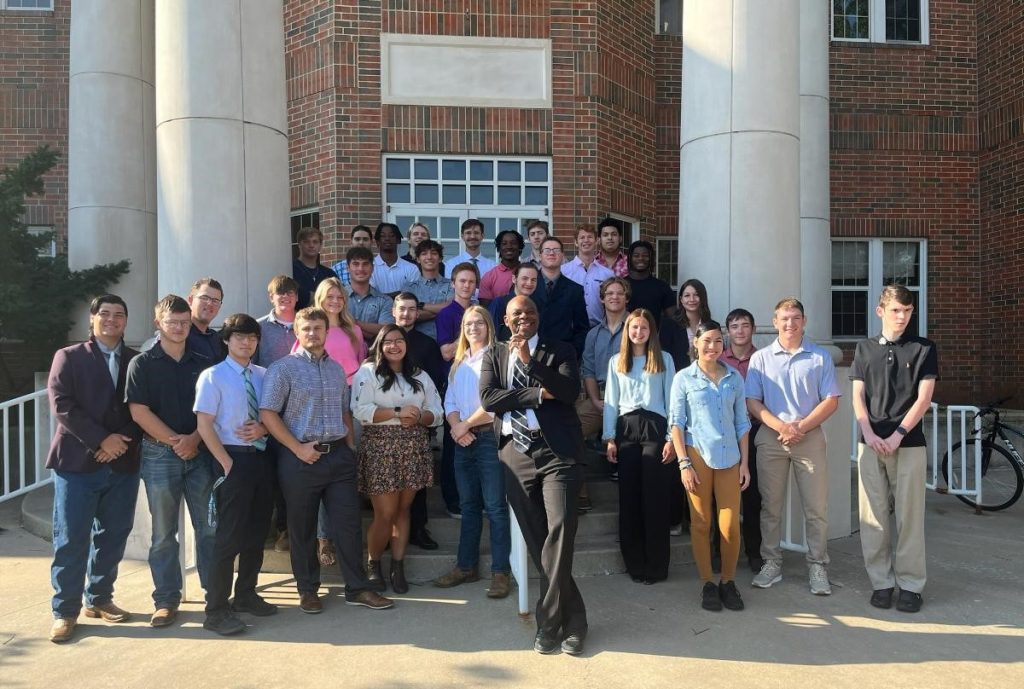 A photo of Dr. Daryl Green and his engineering business communications class, standing outside an academic building.