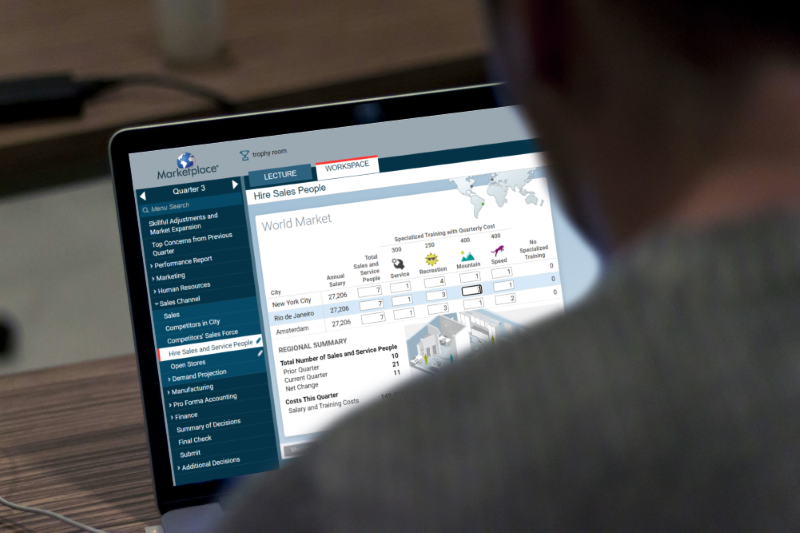 Looking over a man's shoulder as he plays a Marketplace Simulations game. On his computer screen, he is hiring sales people for his stores around the world.